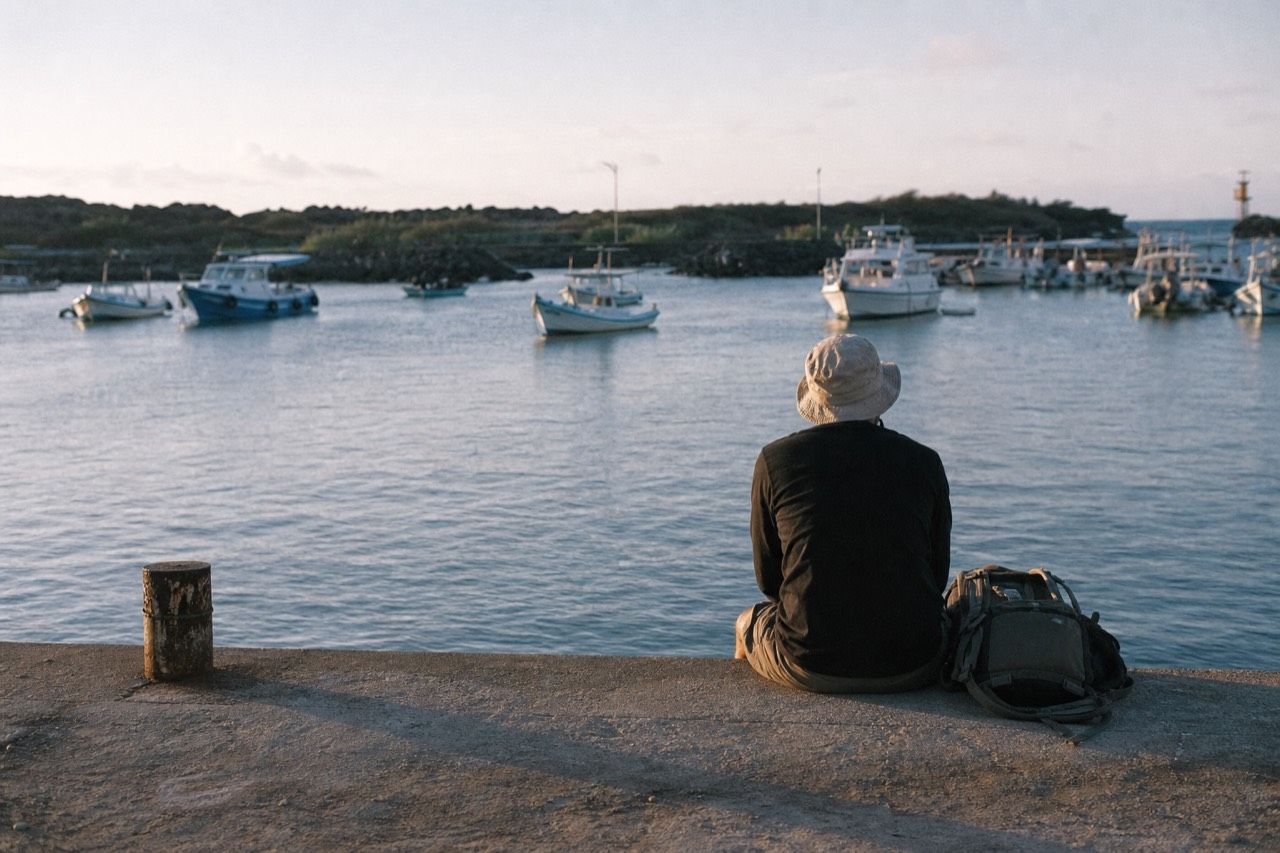 Solo traveller with a daypack waiting on the water taxi dock at Puerto Ayora as a day boat loads passengers