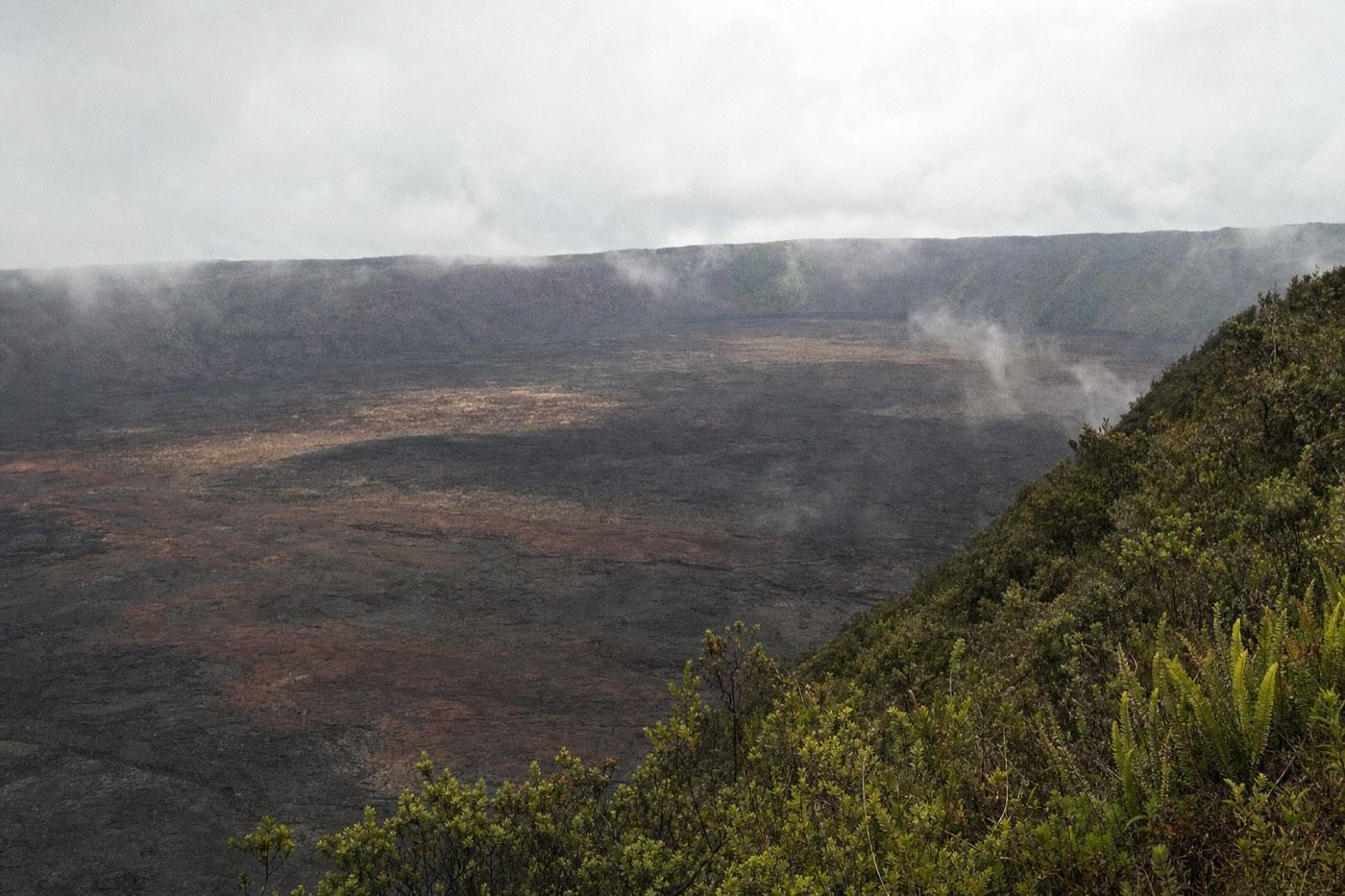 The wide black lava caldera of Sierra Negra volcano on Isabela Island under broken cloud
