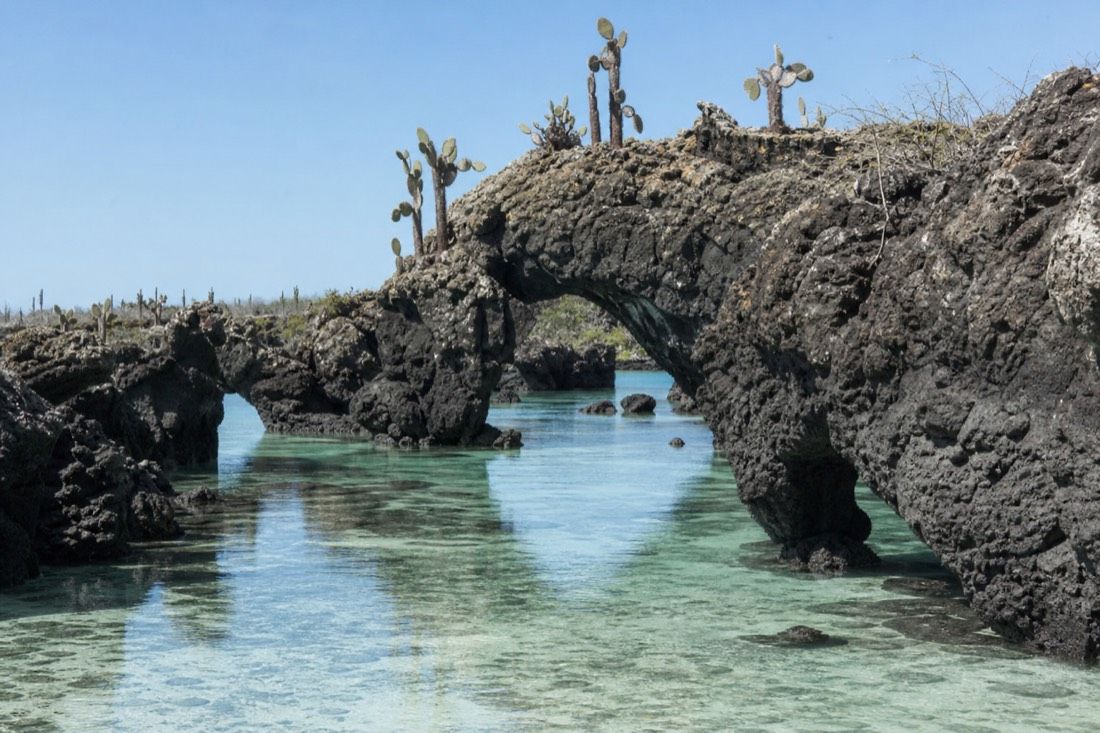 The lava arches of Los Tuneles at Cabo Rosa standing in shallow clear turquoise water